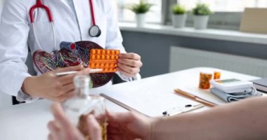 Doctor shows pills to patient for treatment of liver
