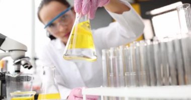 Scientist hands in gloves hold sterile flask with yellow liquid