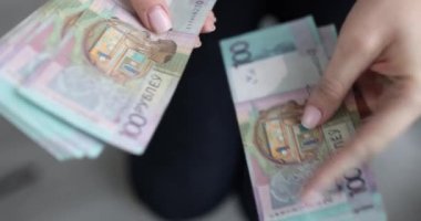 Woman counts Belarusian one hundred ruble banknotes