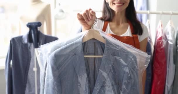 Smiling receptionist at dry cleaning hands over clothes to client — Αρχείο Βίντεο