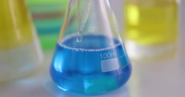 青い液体のサンプルは、ピペットとフラスコから取られます。 — ストック動画