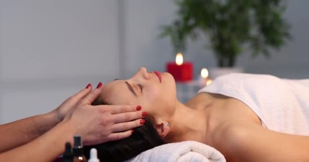 Happy beautiful adult woman with closed eyes receiving head massage with hands — Stockvideo