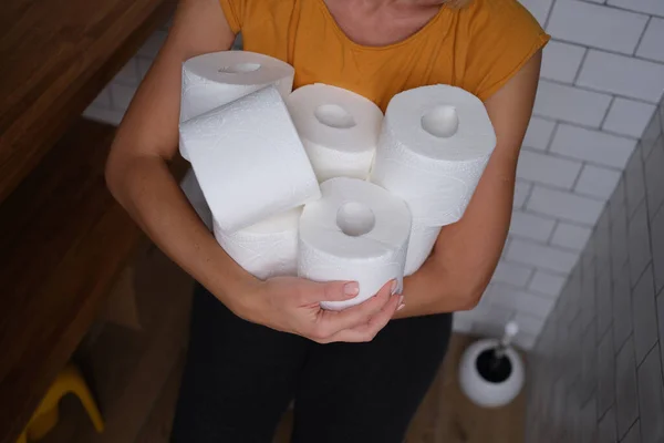 Woman in the wc holds many rolls of toilet paper — Stockfoto