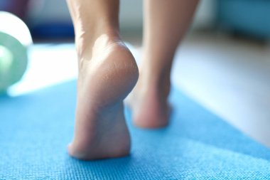 Barefoot dry feet make a step on a blue sports mat