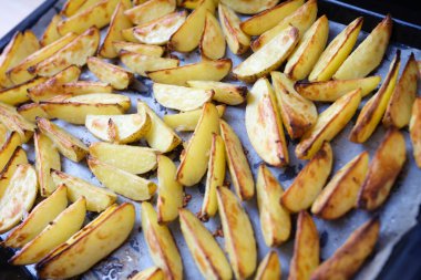 Homemade baked potato wedges on a parchment baking sheet