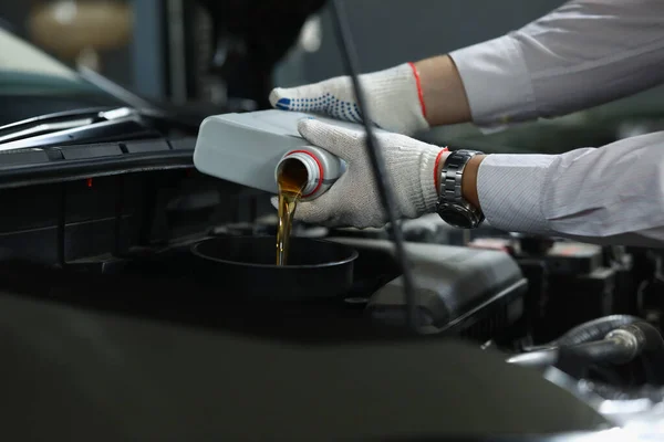 Worker refueling and pouring new oil into engine motor of automobile — Stock Photo, Image