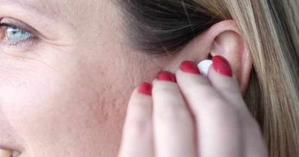 Vrouw plaatst draadloze hoofdtelefoon in het oor — Stockvideo