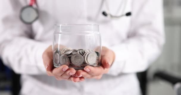 Doktor v bílém plášti drží sklenici mincí zpomalený film 4k — Stock video