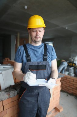 Meşgul profesyonel işçi panosu ve gerekli iş materyallerini tutuyor