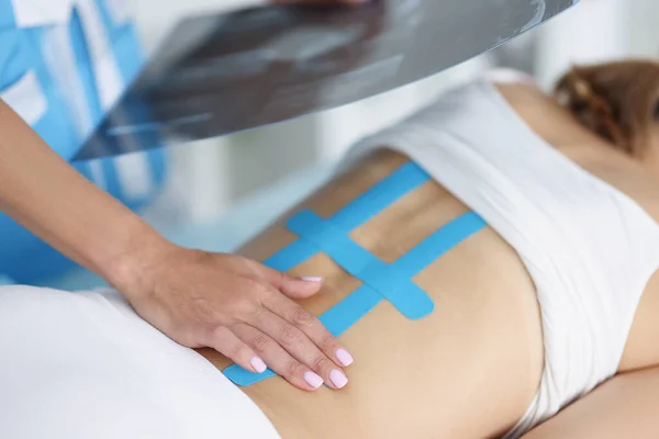 Žena lékař držet skenování ženy zpět a správné kineziologické pásky na ženské tělo — Stock fotografie