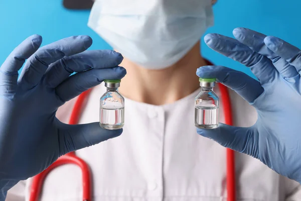 Cientista segurando dois frascos com injeção em luvas azuis — Fotografia de Stock