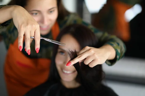 Il parrucchiere professionista concentrato tiene la serratura di capelli e il taglio con forbici — Foto Stock