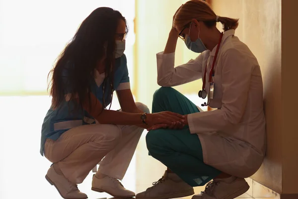 Un medico donna calma un collega stanco — Foto Stock