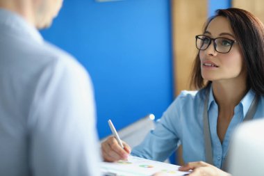 Ofisteki bir kadın, bir adama bir rapor açıklar.