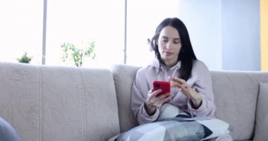 Akıllı telefon kullanan rahat genç bir kadın sosyal medyaya girip haberleri kontrol ediyor.