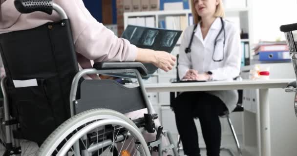 Tekerlekli sandalyedeki kadın doktorla omurga röntgenini tartışıyor. — Stok video