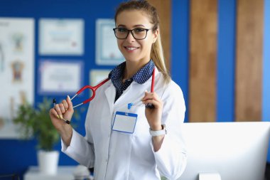 Güzel bayan doktor gülümsüyor, klinikte duruyor.