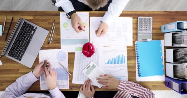 Equipo de negocios lanza monedas en alcancía en el lugar de trabajo — Vídeo de stock