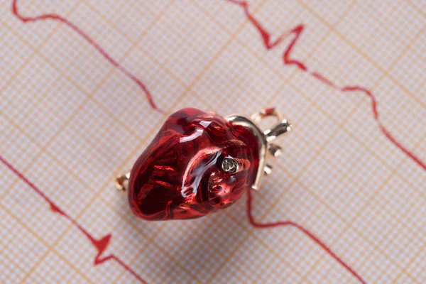 Kalp kardiyogramının üzerine yerleştirilmiş kırmızı cam minyatür kalp sonuç kağıdı — Stok fotoğraf