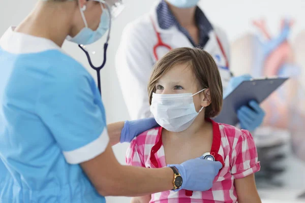 Врач-педиатр со стетоскопом слушает маленькую девочку дыхание и сердцебиение по назначению — стоковое фото