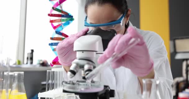 Wissenschaftler Chemiker gießt rosa Flüssigkeit aus Reagenzglas vor dem Mikroskop in Labor 4k Film Zeitlupe — Stockvideo