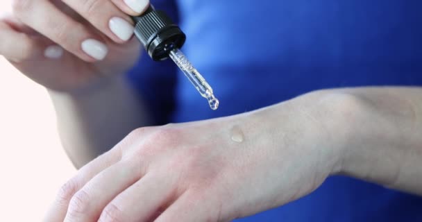 Mulher gotejamento gotas de óleo cosmético em suas mãos closeup filme 4k — Vídeo de Stock
