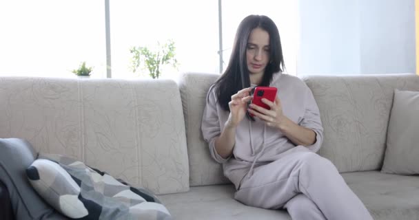 Mujer leyendo noticias en su teléfono y cayendo en la película sofá 4k — Vídeos de Stock