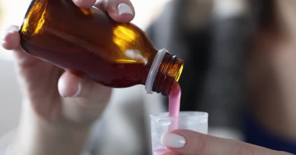 Doente mãos mulher derramando xarope de tosse em medir copo closeup filme 4k — Vídeo de Stock