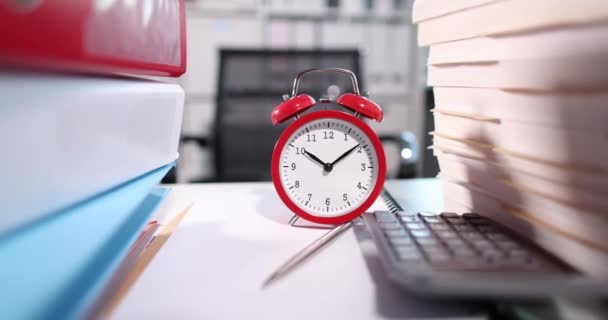 Reloj despertador rojo de pie sobre la mesa entre carpetas con documentos y calculadora 4k película cámara lenta — Vídeos de Stock