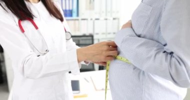 Doktor kadın doğum uzmanı-jinekolog, 4K bant kullanarak hamile bir kadının karnının hacmini ölçüyor.