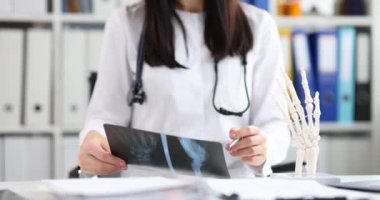 Doktor travmatolog, insan palmiyesi filminin yapay modelinin arka planındaki el röntgenine bakıyor.