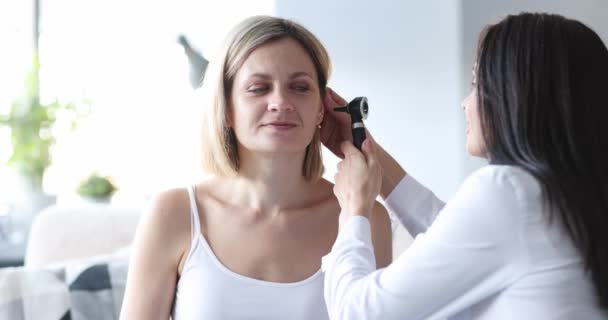 Doktor při pohledu na ucho s otoskopem na ženu pacienta doma 4k film — Stock video