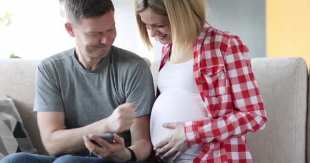 Casado casal olhando para o telefone celular e colocá-lo na barriga da esposa grávida filme 4k — Vídeo de Stock