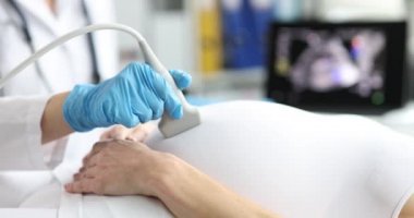 Doktor klinikte hamile bir kadına ultrason yapıyor. 4K film, ağır çekim.