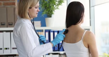 4K filminde steteskopla hastanın ciğerlerini dinleyen kadın doktor.