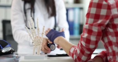 Doktor travmatolog kırık kolu klinikteki hastaya bandajlıyor. 4K film.