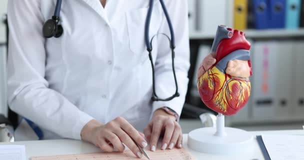 Lékař kardiolog vyšetřuje kardiogram pacienta na klinice — Stock video