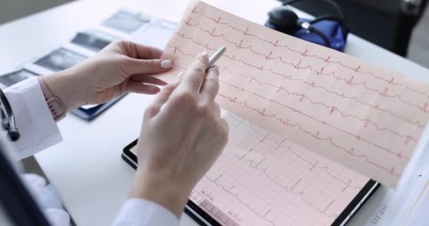Врач-кардиолог изучает электрокардиограмму на планшетах крупным планом — стоковое видео