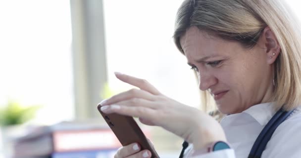 Tired sad woman doctor looks into smartphone closeup — Stock Video