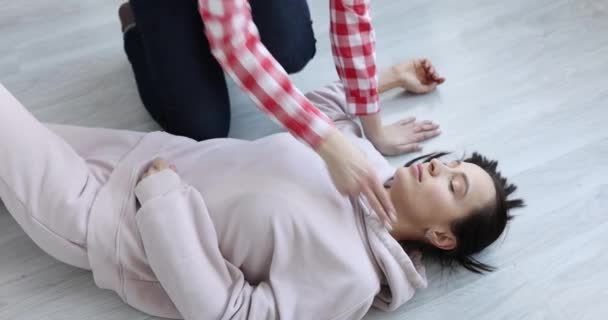 Mladá žena leží v bezvědomí na podlaze a dělá masáž srdce detailní — Stock video