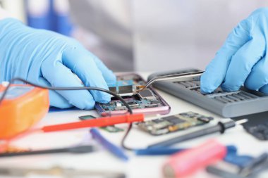 Usta tamirci cep telefonuna mikroçip yerleştiriyor.