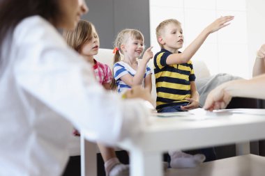 Çocuklar ve ebeveynler evde masa oyunu oynuyorlar.