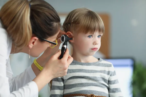 Női gyermekorvos, aki egy kislány fülét nézi, aki otoszkópot használ a klinikán — Stock Fotó