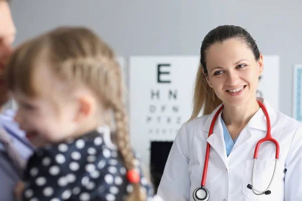 Uśmiechnięta lekarka stojąca blisko małej dziewczynki w klinice — Zdjęcie stockowe