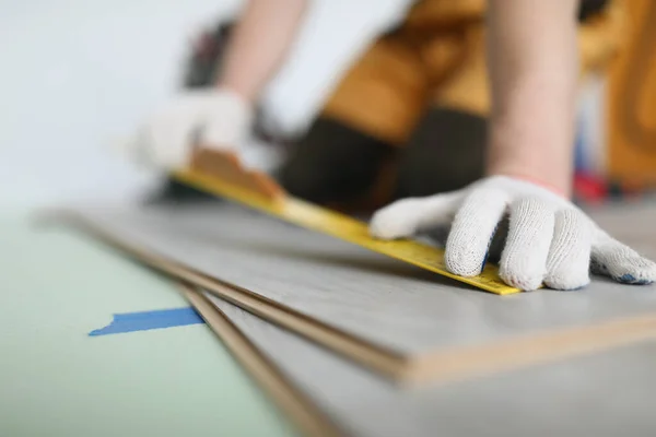 Man builder mäta laminat styrelse med linjal för att lägga golv närbild — Stockfoto