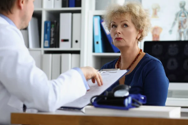Doctor interviewing elderly woman patient in clinic office