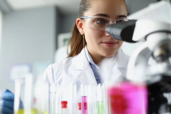 Kvinna vetenskapsman kemist tittar igenom mikroskop i laboratorium — Stockfoto