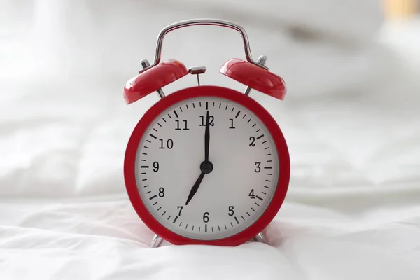 Roter Wecker für 7 Stunden auf weißem Bett in Nahaufnahme — Stockfoto