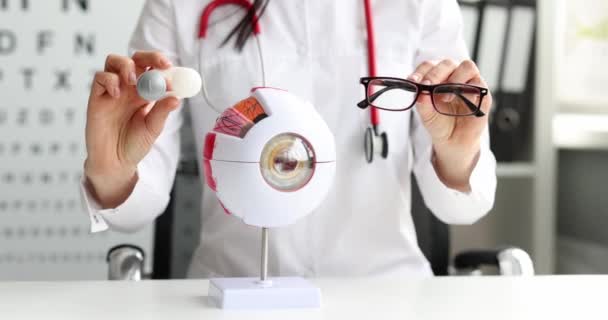 Врач-офтальмолог держит очки и контактные линзы вблизи — стоковое видео