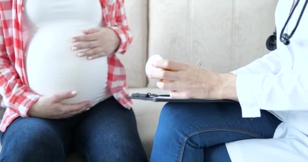La femme enceinte est assise sur le canapé, le médecin donne des pilules en gros plan — Video